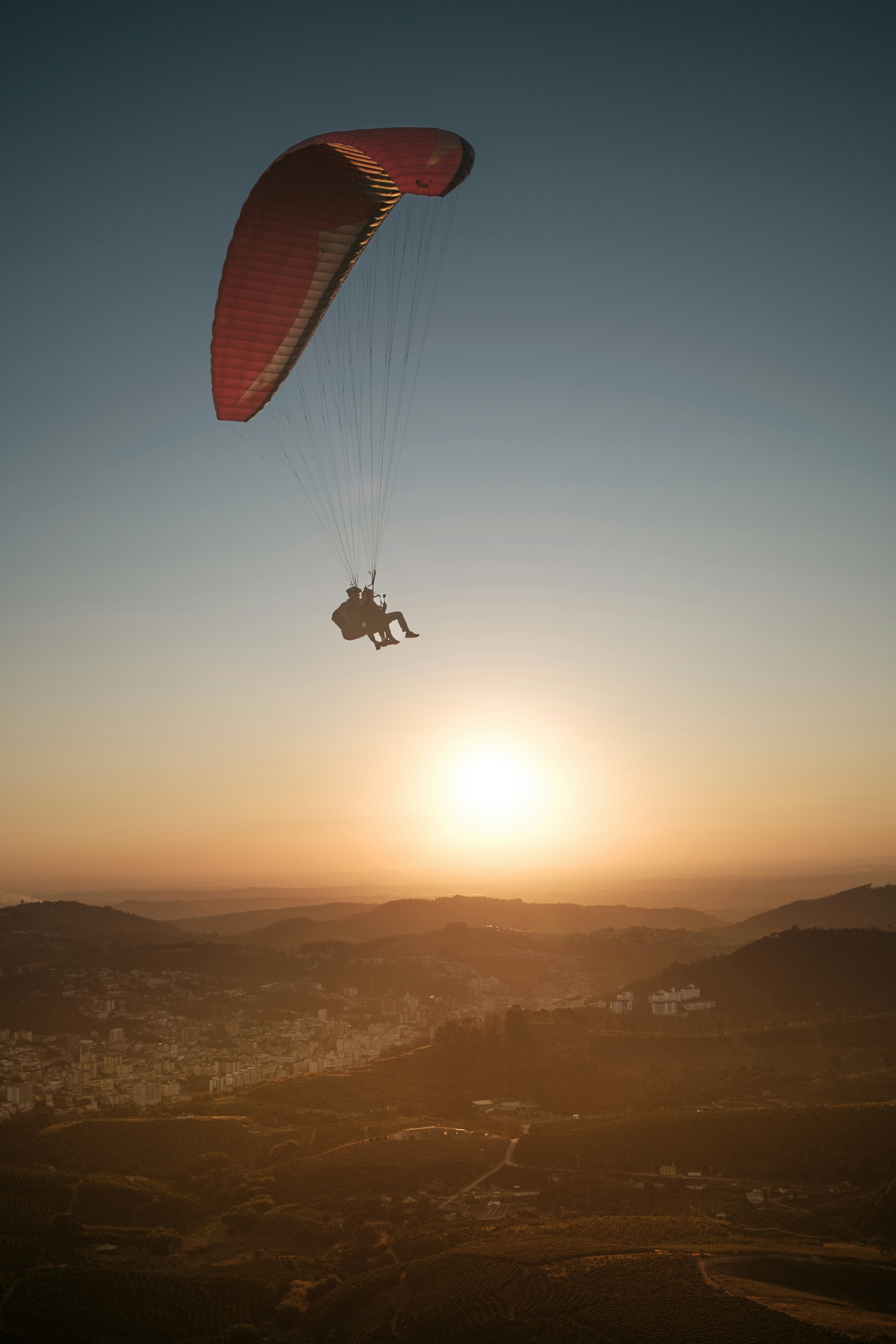 Paragliders soar into the sunset.