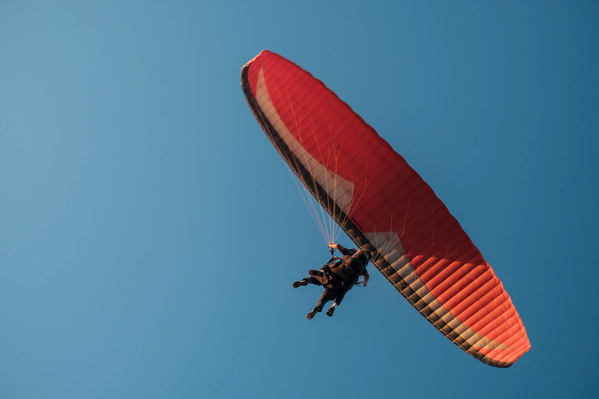 A paraglider soars high in the blue sky