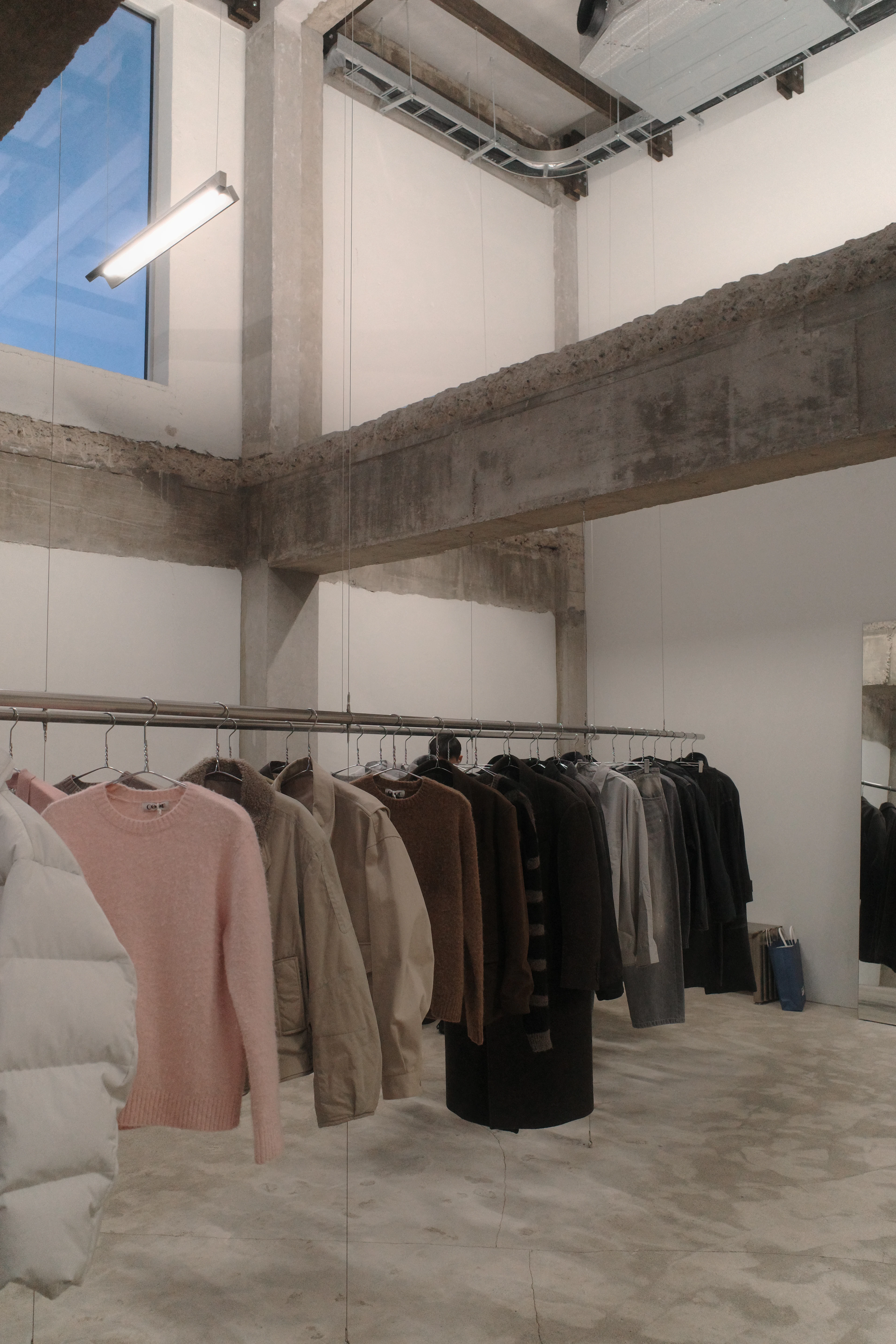 Clothes hanging on a rail in a bright, minimal shop