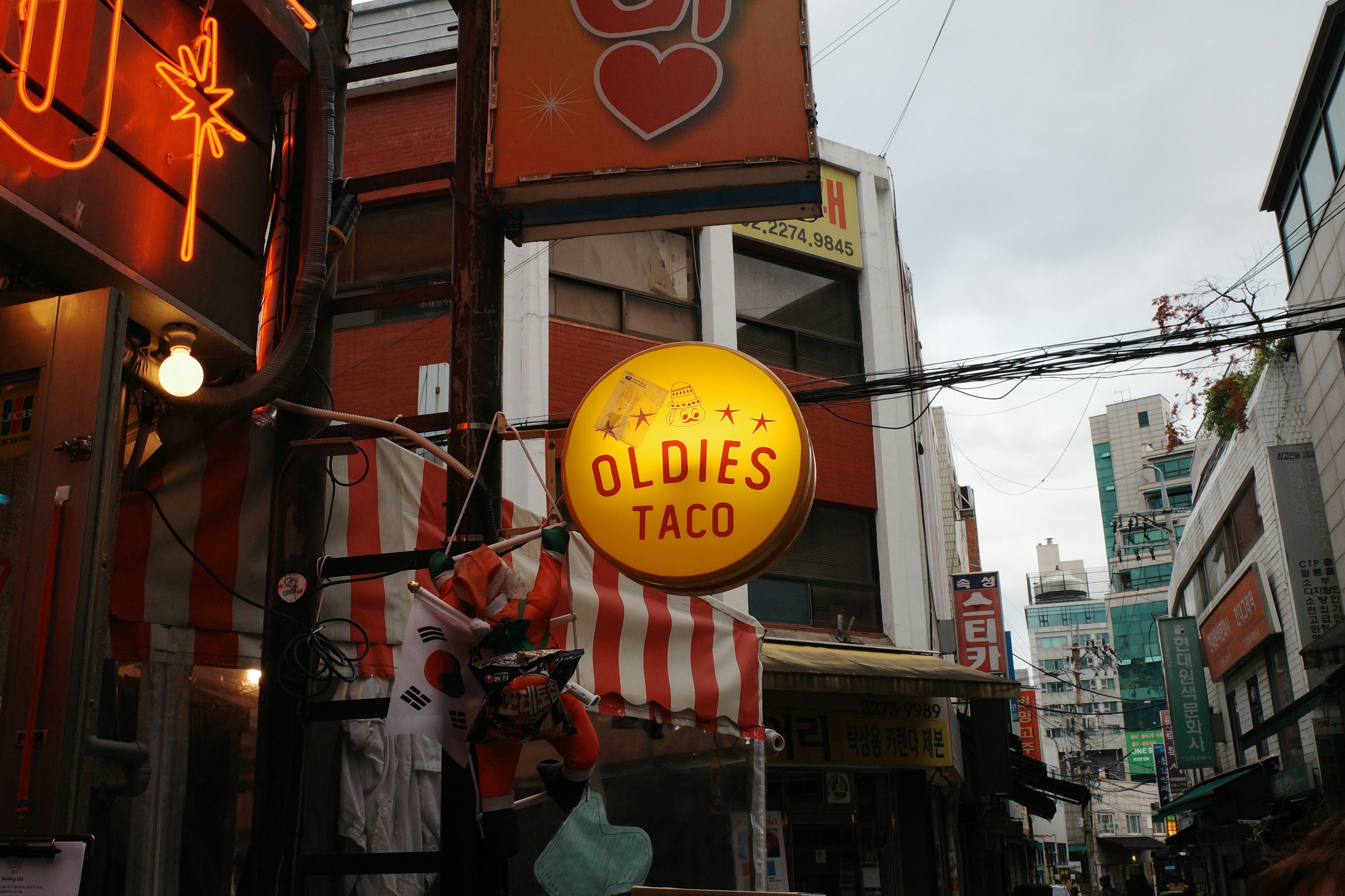 Ein "Oldies Taco"-Schild hängt an einer Straße in der Stadt.
