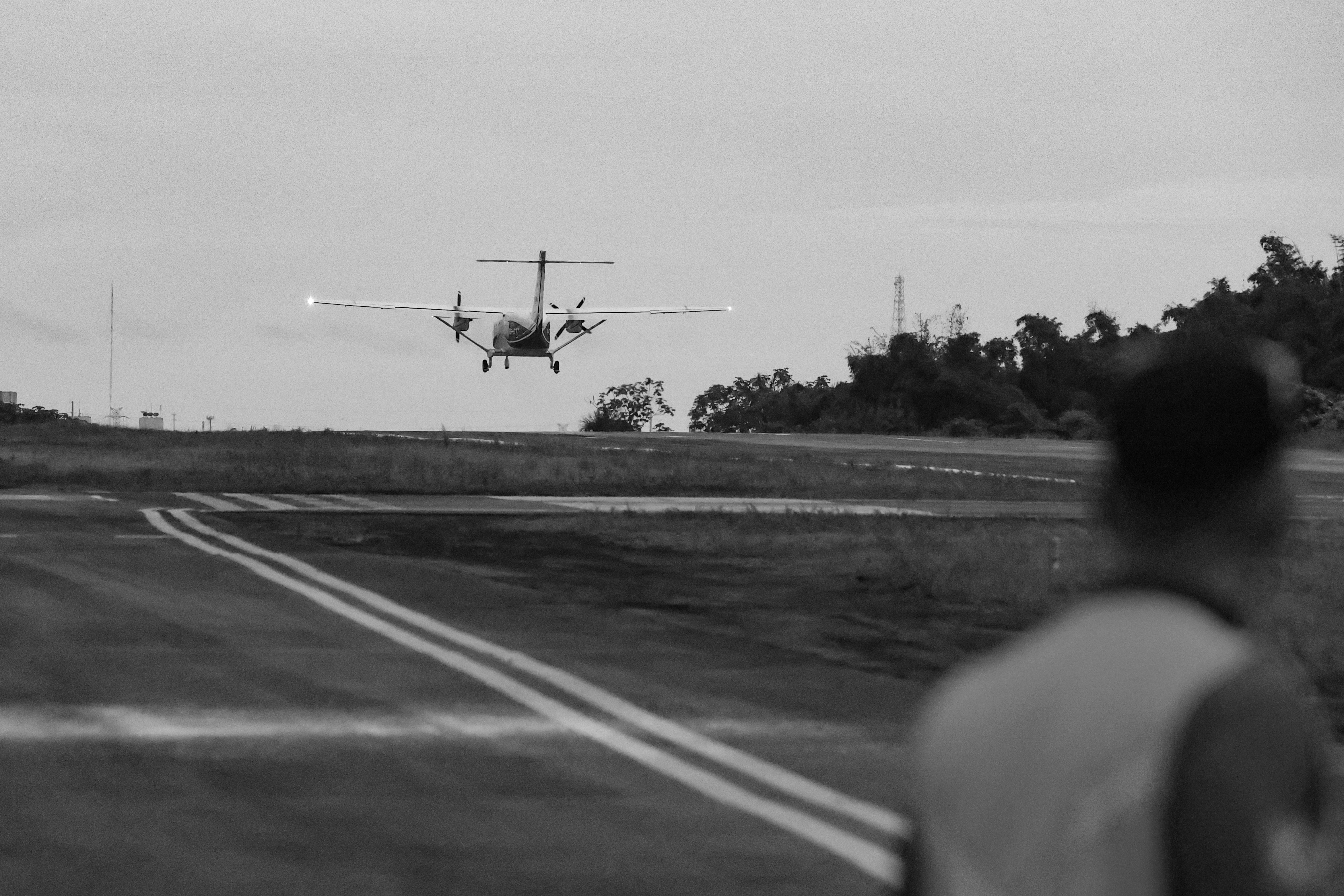 Um avião pousa na pista em preto e branco.