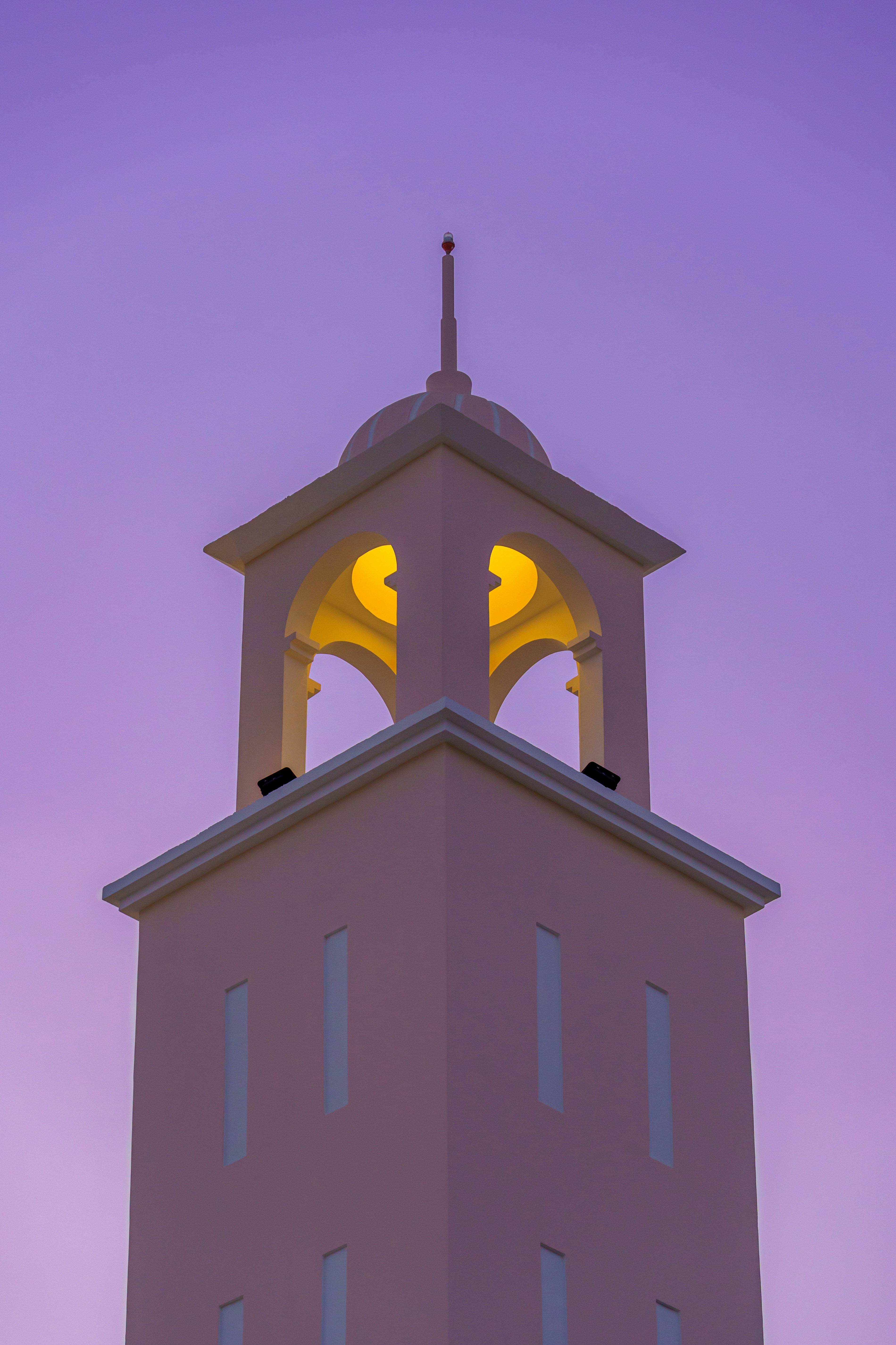 A tall tower illuminated against a purple sky.