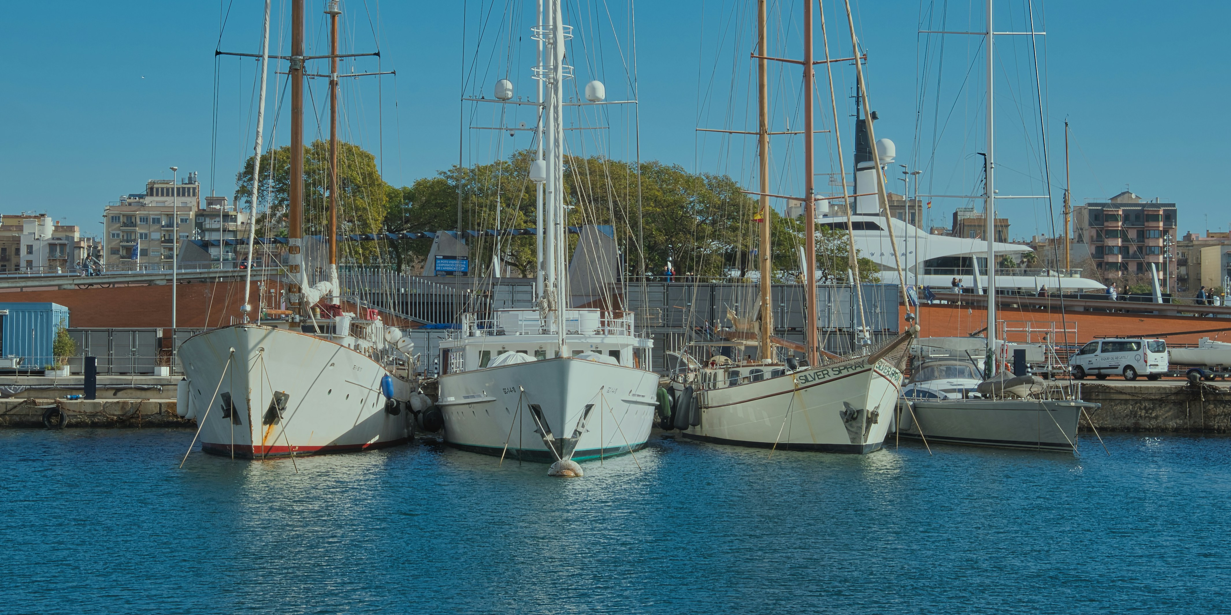 Sailboats are docked in the harbor on a sunny day.