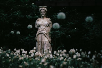 Ancient statue surrounded by flowers and foliage.