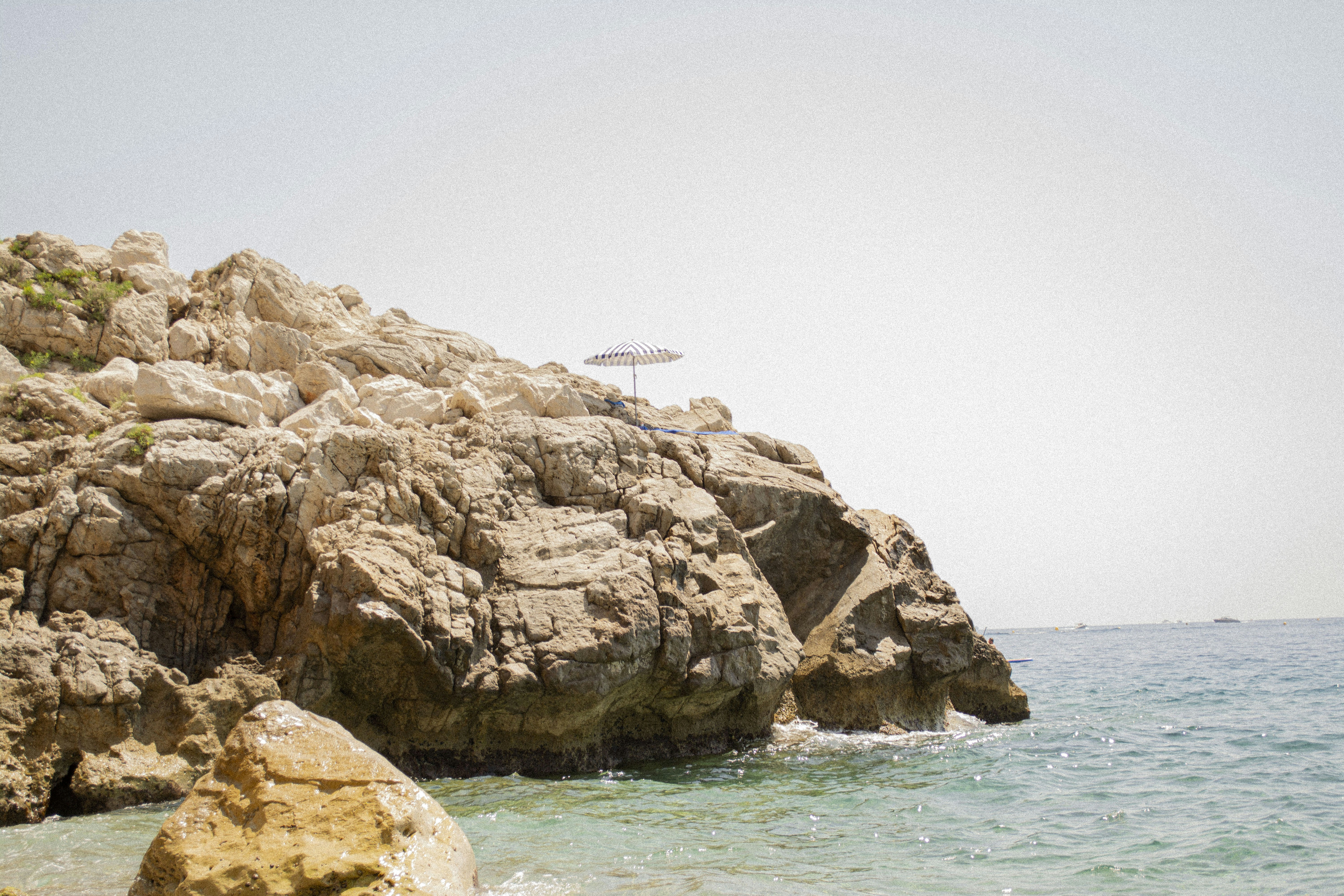 Rocky cliffs meet the ocean on a sunny day.