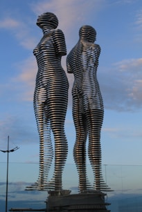 Two metal sculptures stand tall against a sky.