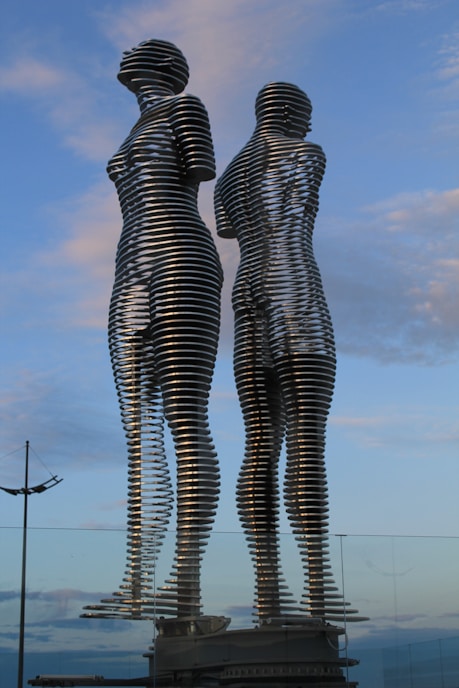 Two metal sculptures stand tall against a sky.