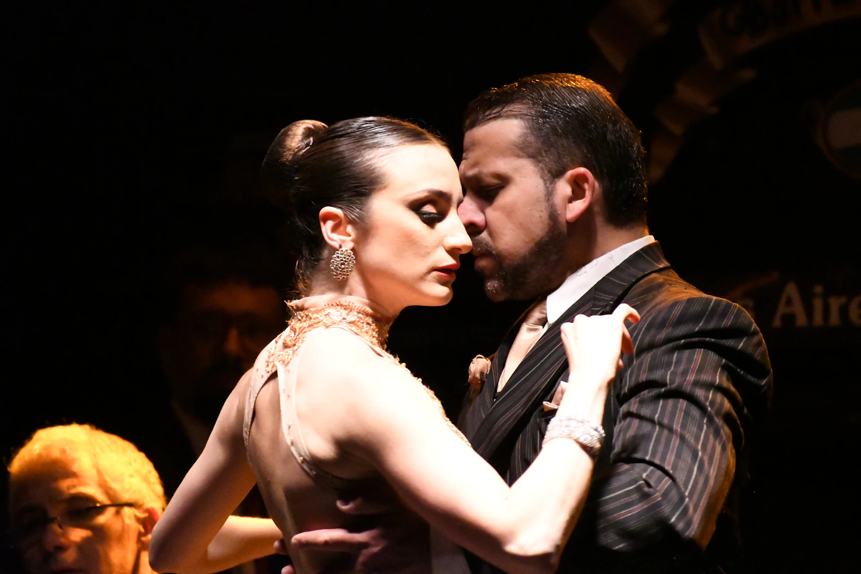 A tango couple dancing closely during a live performance in Buenos Aires