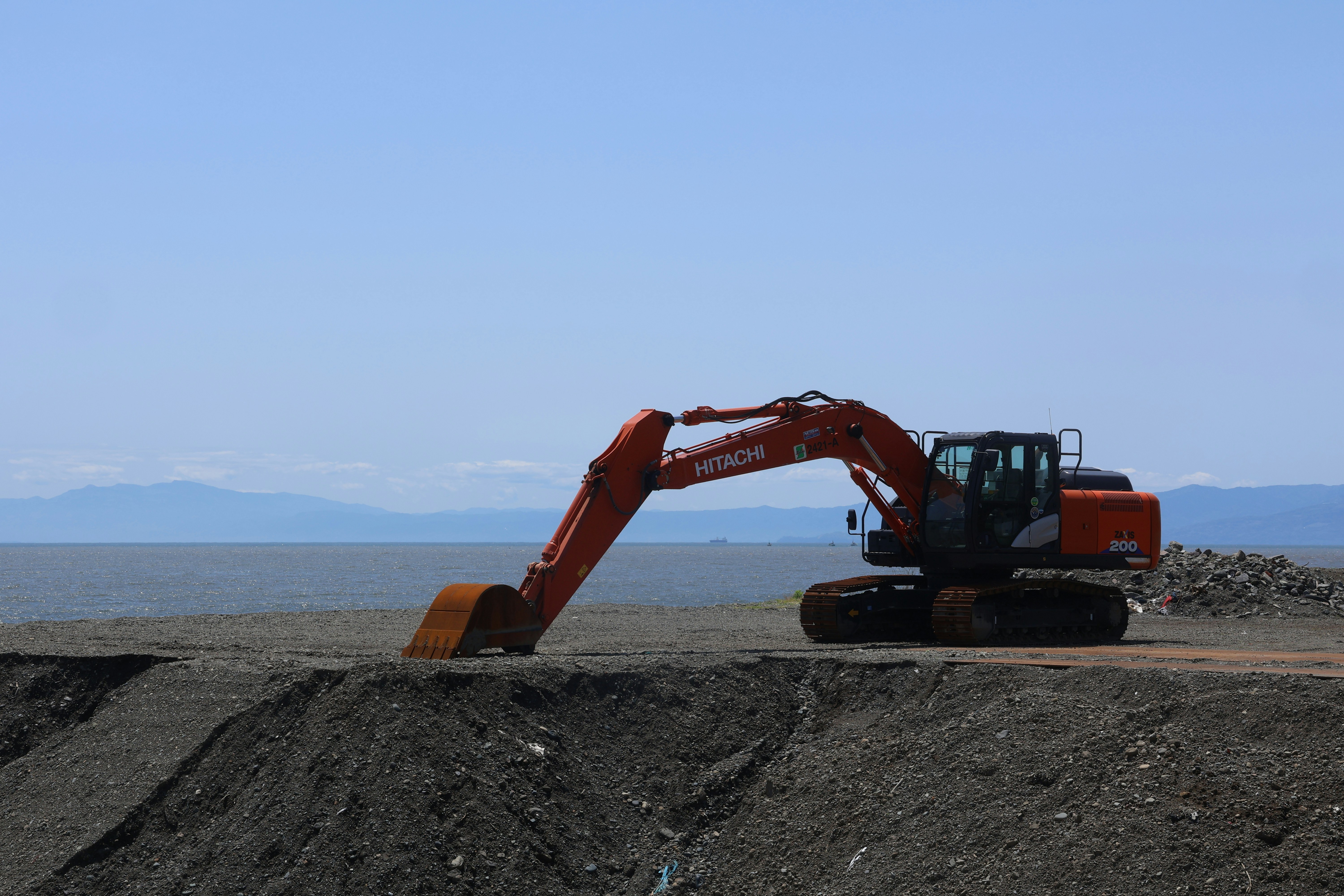 An excavator works by the water.