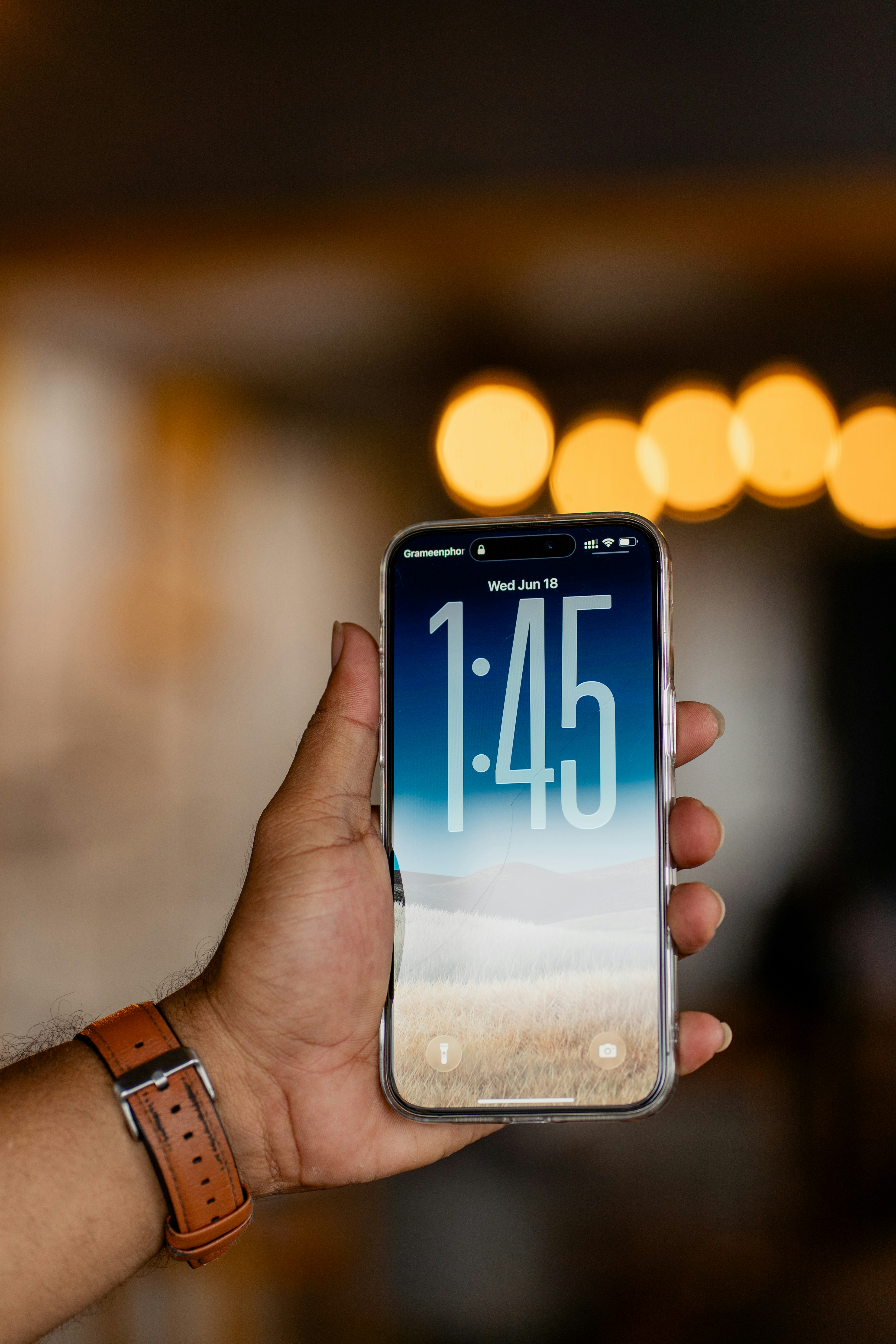 A hand holds a phone with the time displayed