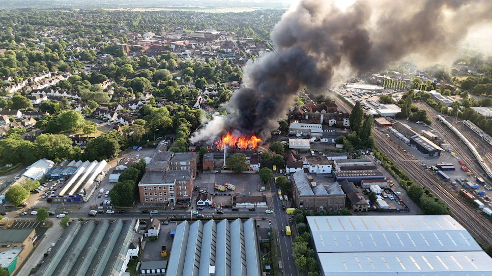 A large fire engulfs a building, releasing smoke.