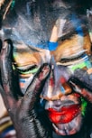 A face is covered in vibrant, abstract paint.