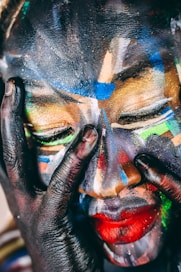 A face is covered in vibrant, abstract paint.
