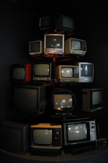 Old televisions are stacked in a creative display.