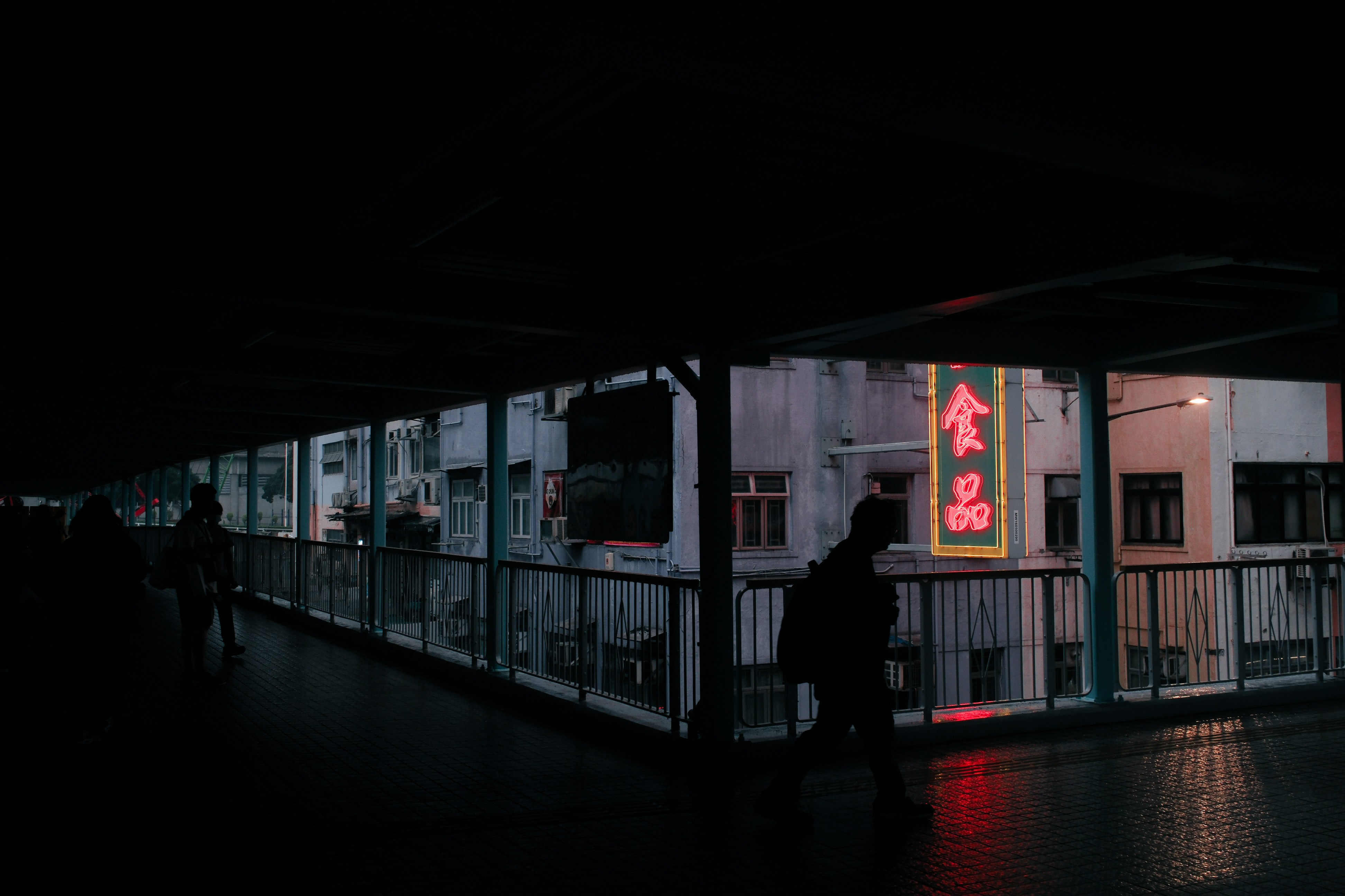 People walk on a bridge at night.