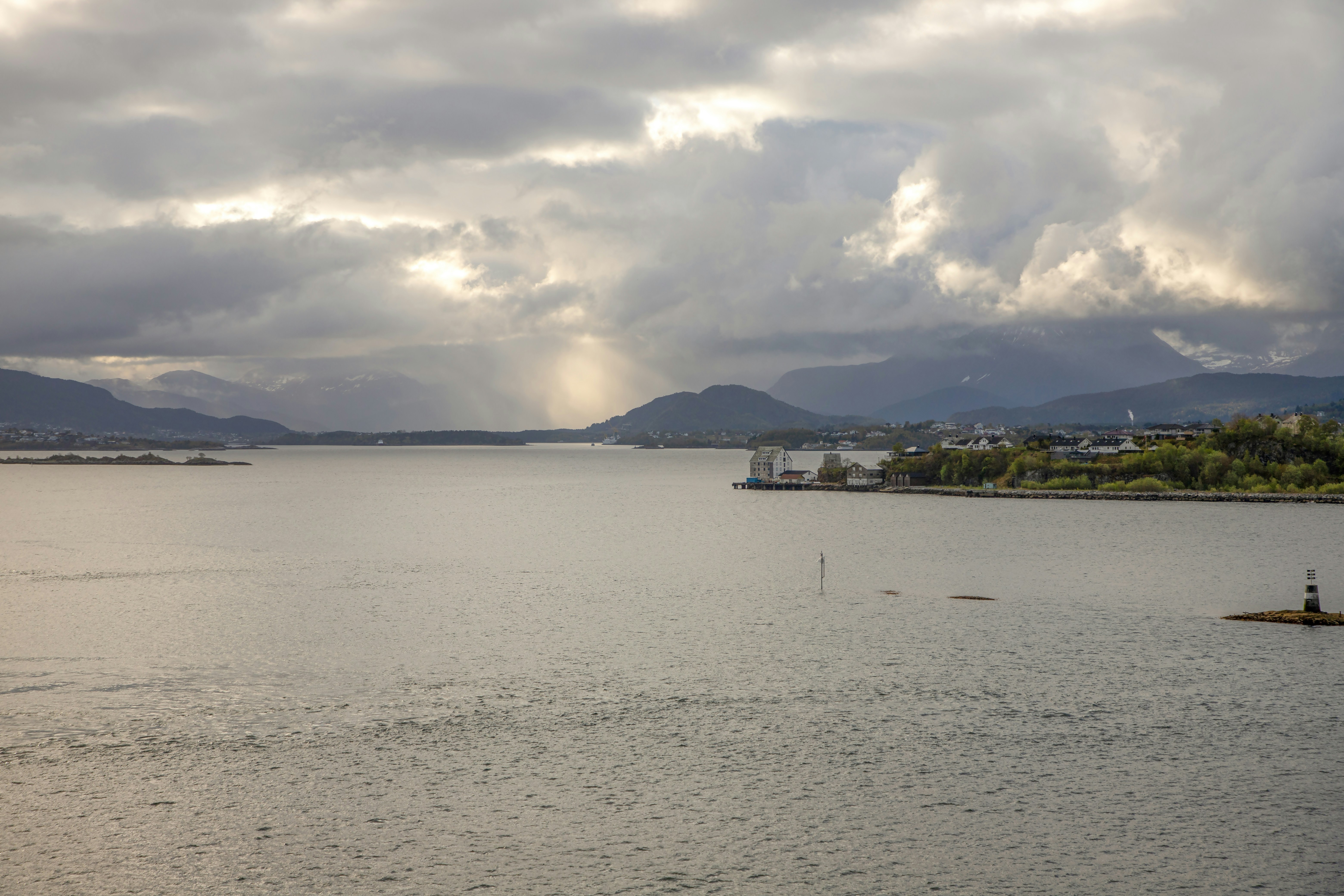 Sunlight streams through clouds over a calm body of water.