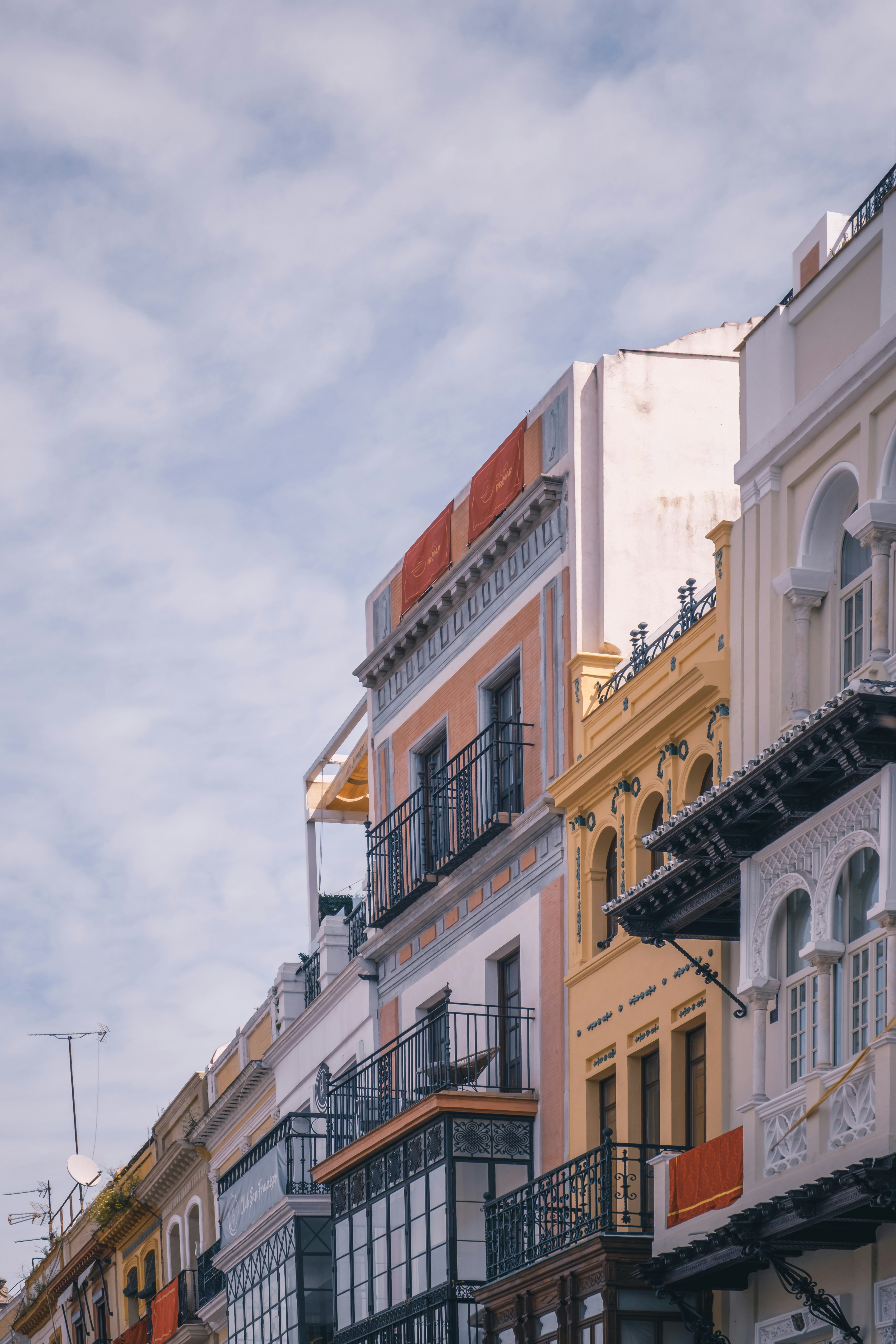 Colorful buildings line a cloudy, bright sky.