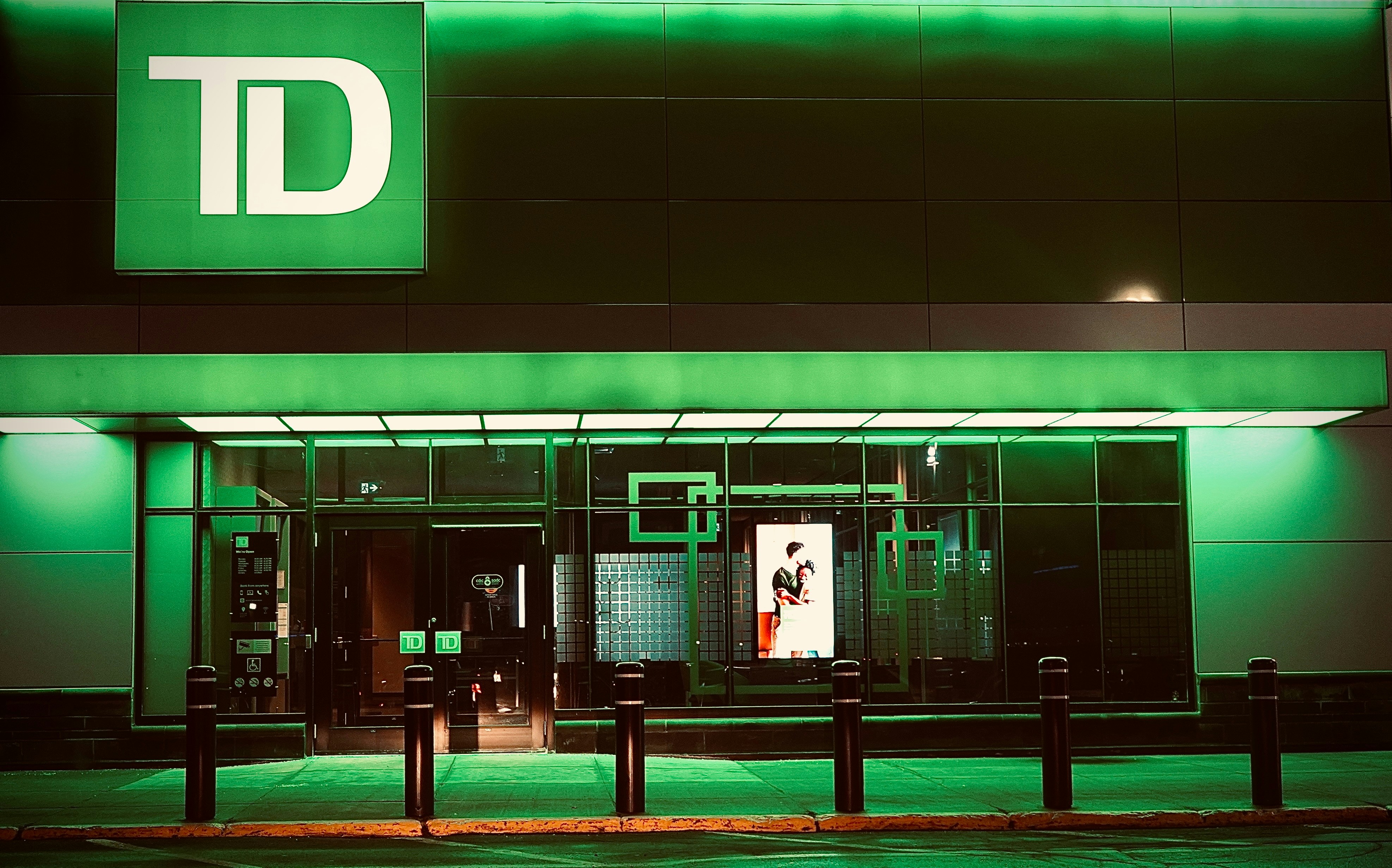 A td bank branch glows with green lighting.