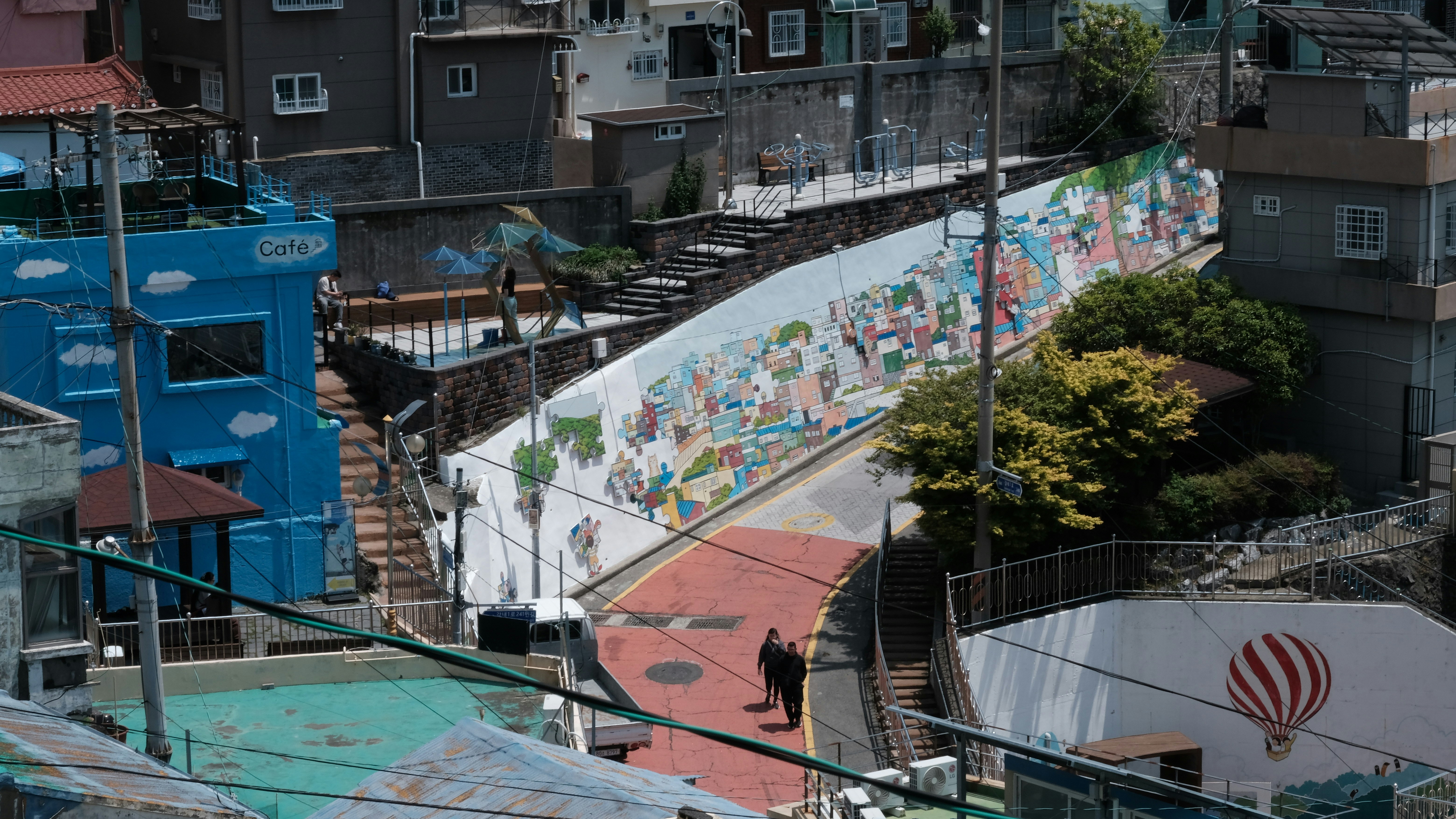 A mural-covered wall slopes down a narrow street
