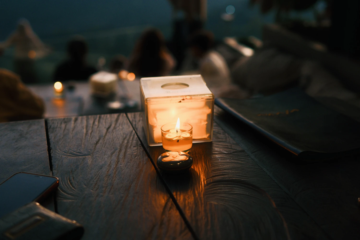 Candles burning along a table at dusk with the room going dark behind them