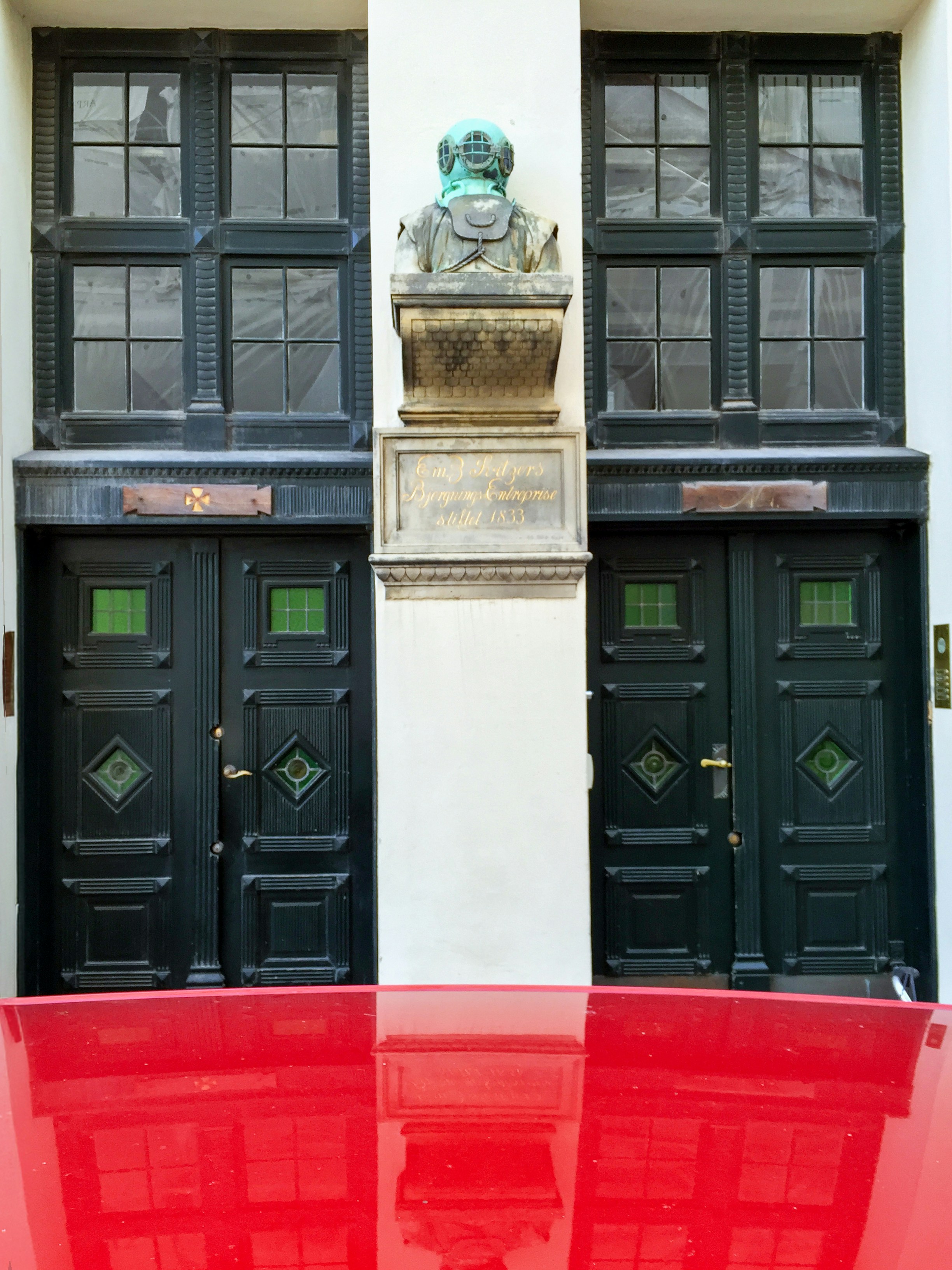 Two doors flank a statue and reflection.