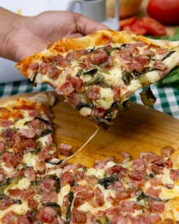 Someone is holding a delicious slice of pizza.