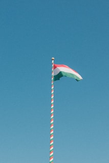 The hungarian flag flies against a clear blue sky.