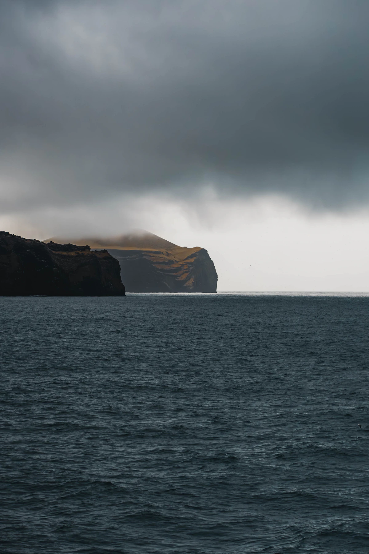 Dark sea and cliffs under a heavy, clouded sky