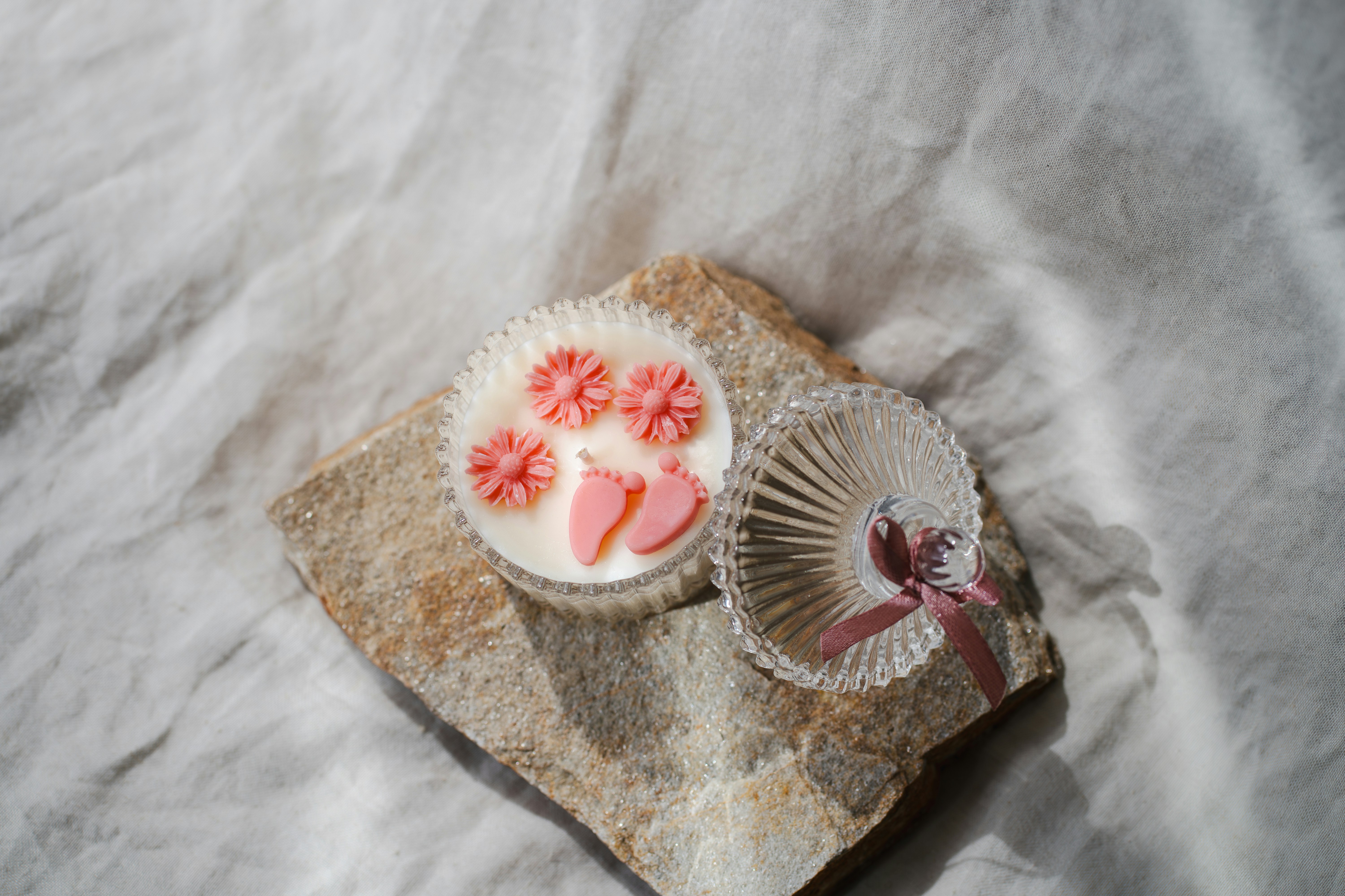Candle with decorations and a small, clear dish.