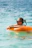 A woman floats in the ocean with a tube.