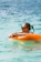 A woman floats in the ocean with a tube.
