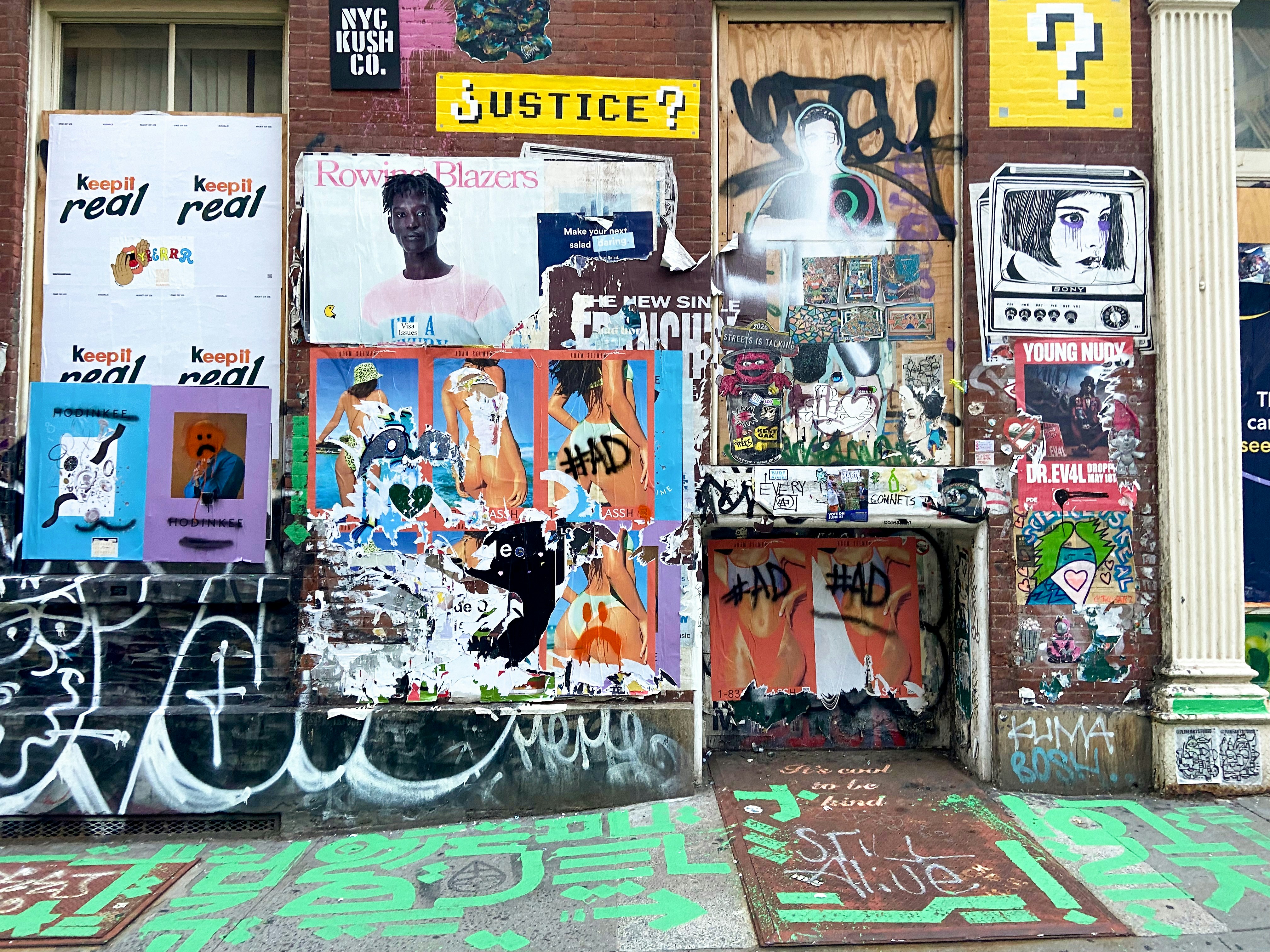 The image shows a brick wall covered in posters.