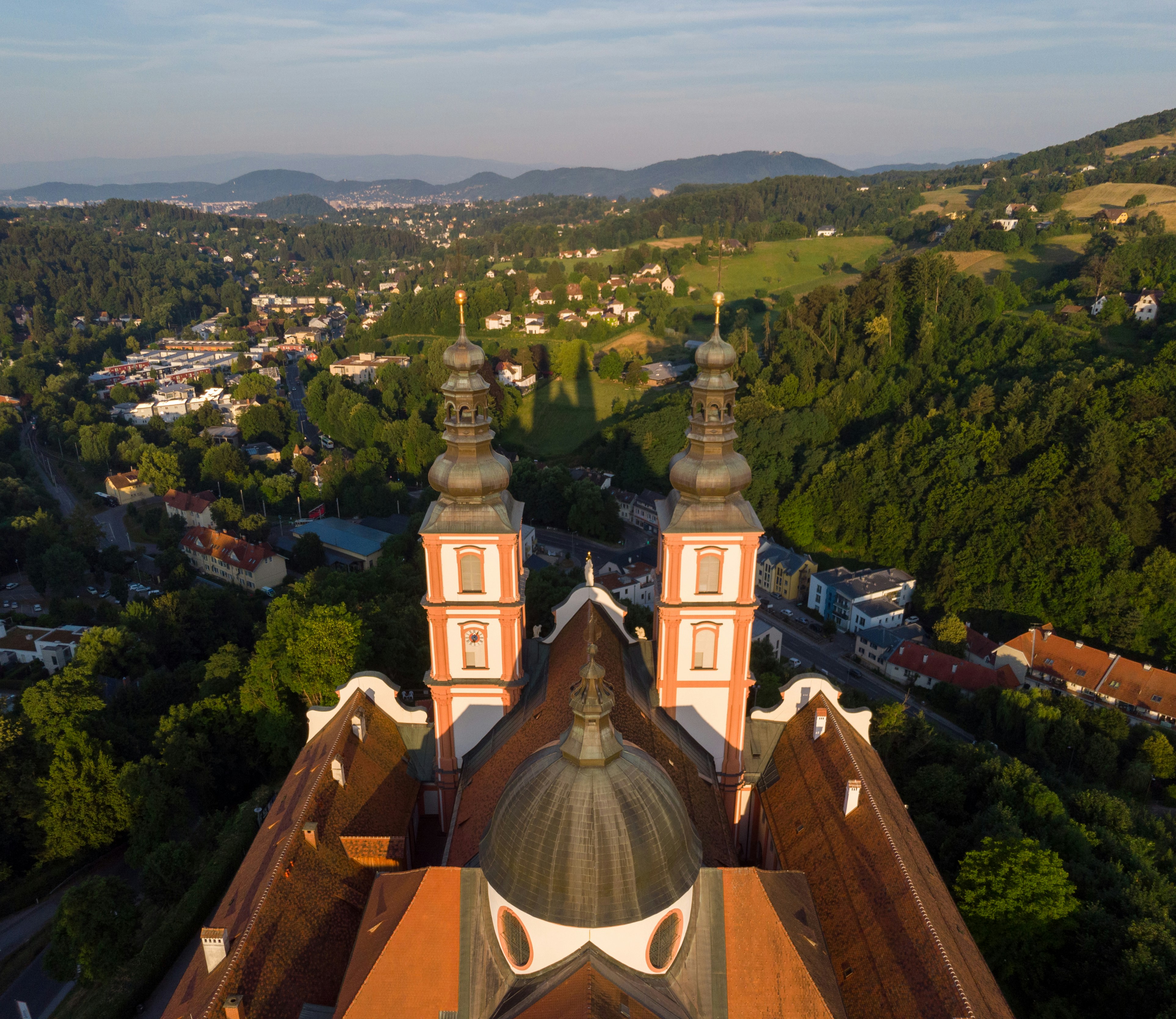A church with two spires overlooks a valley.