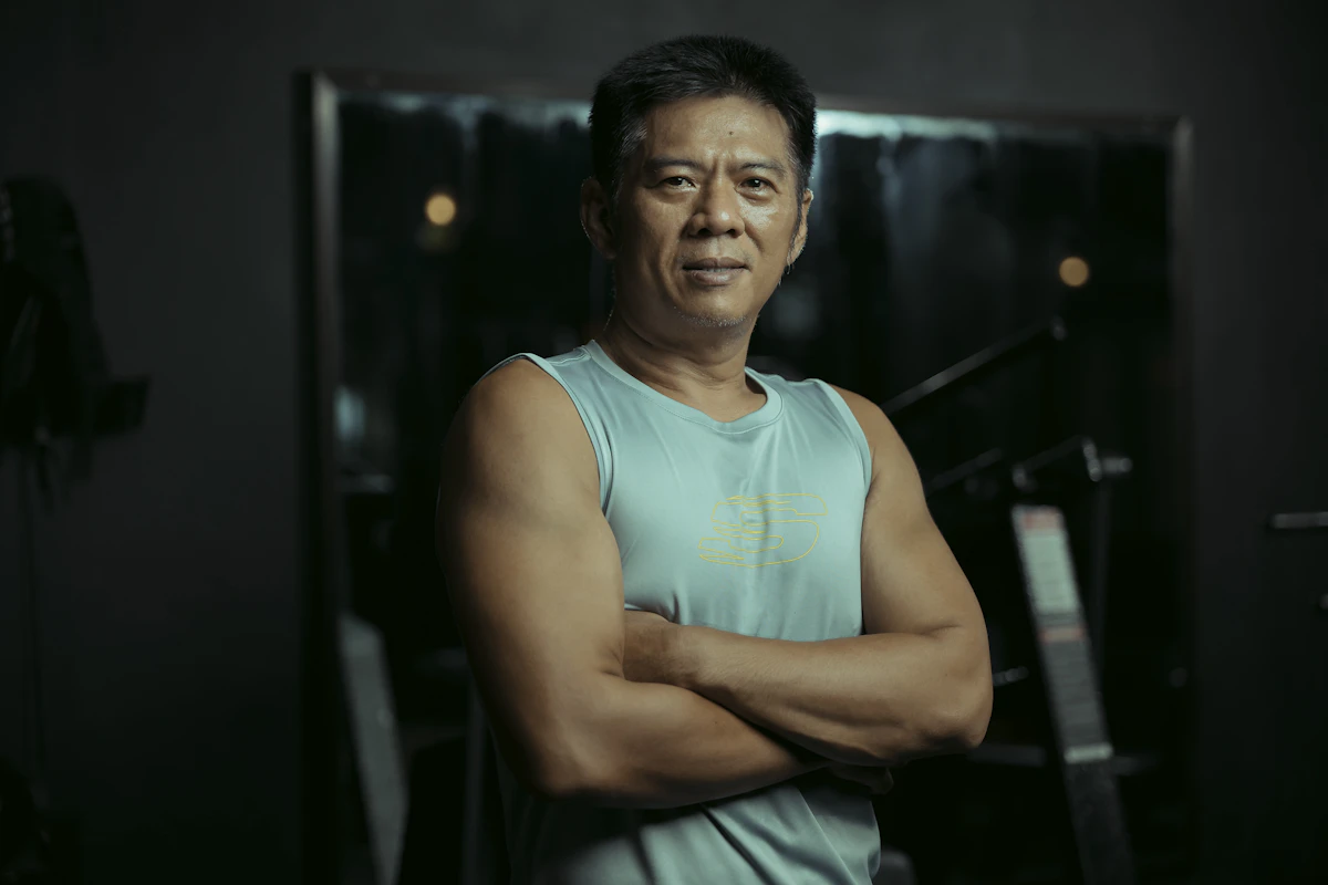 Fit adult man standing with arms crossed in a gym
