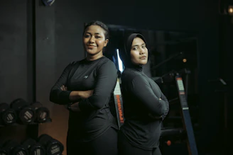 Two women stand together confidently in a gym.