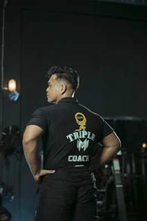 A muscular man poses, back turned.