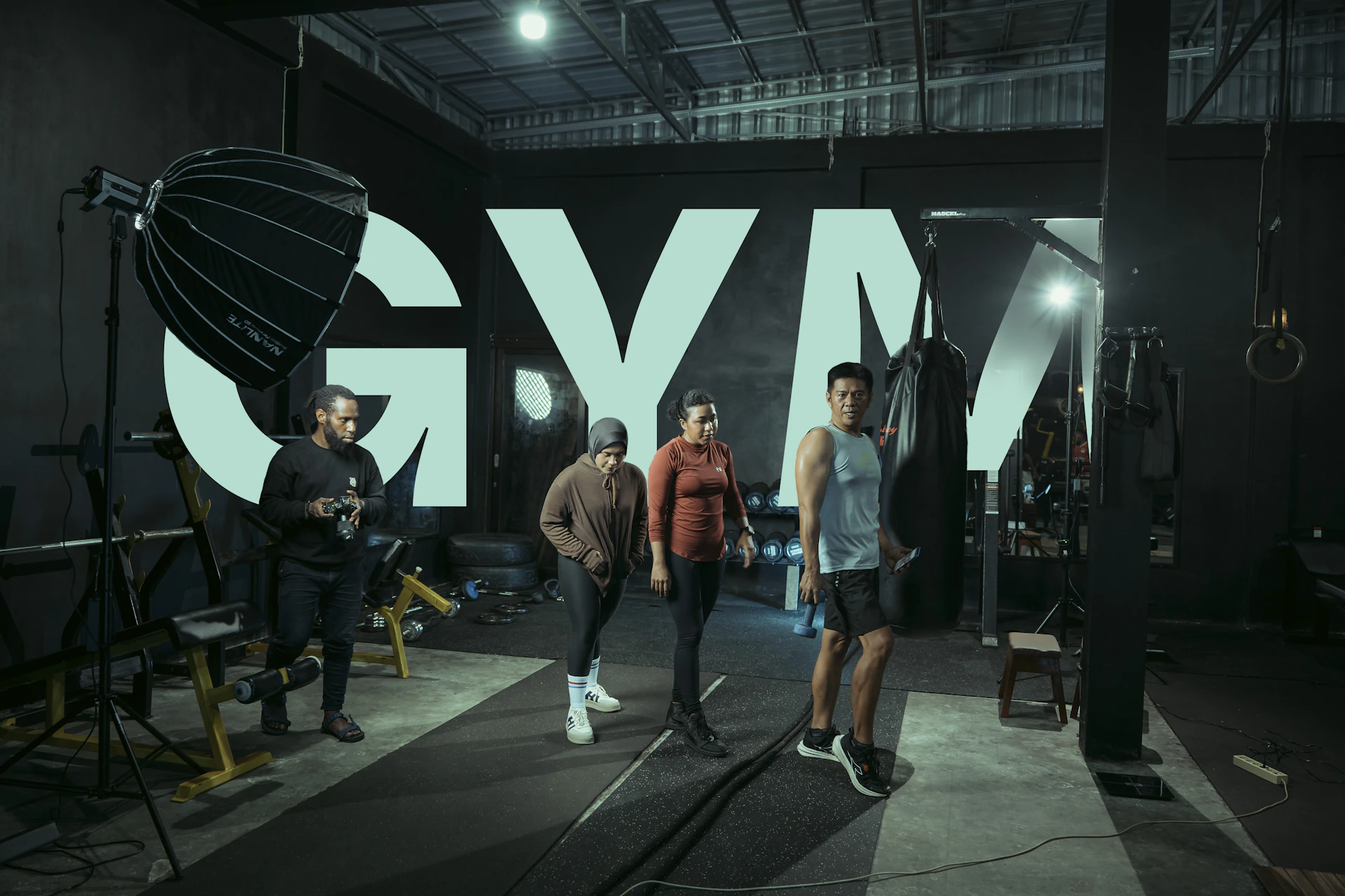 People pose in front of a large "gym" sign.