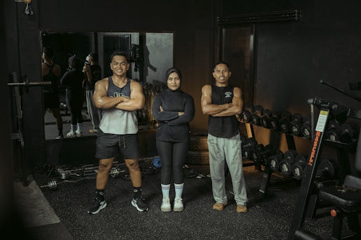 Three people pose at the gym.