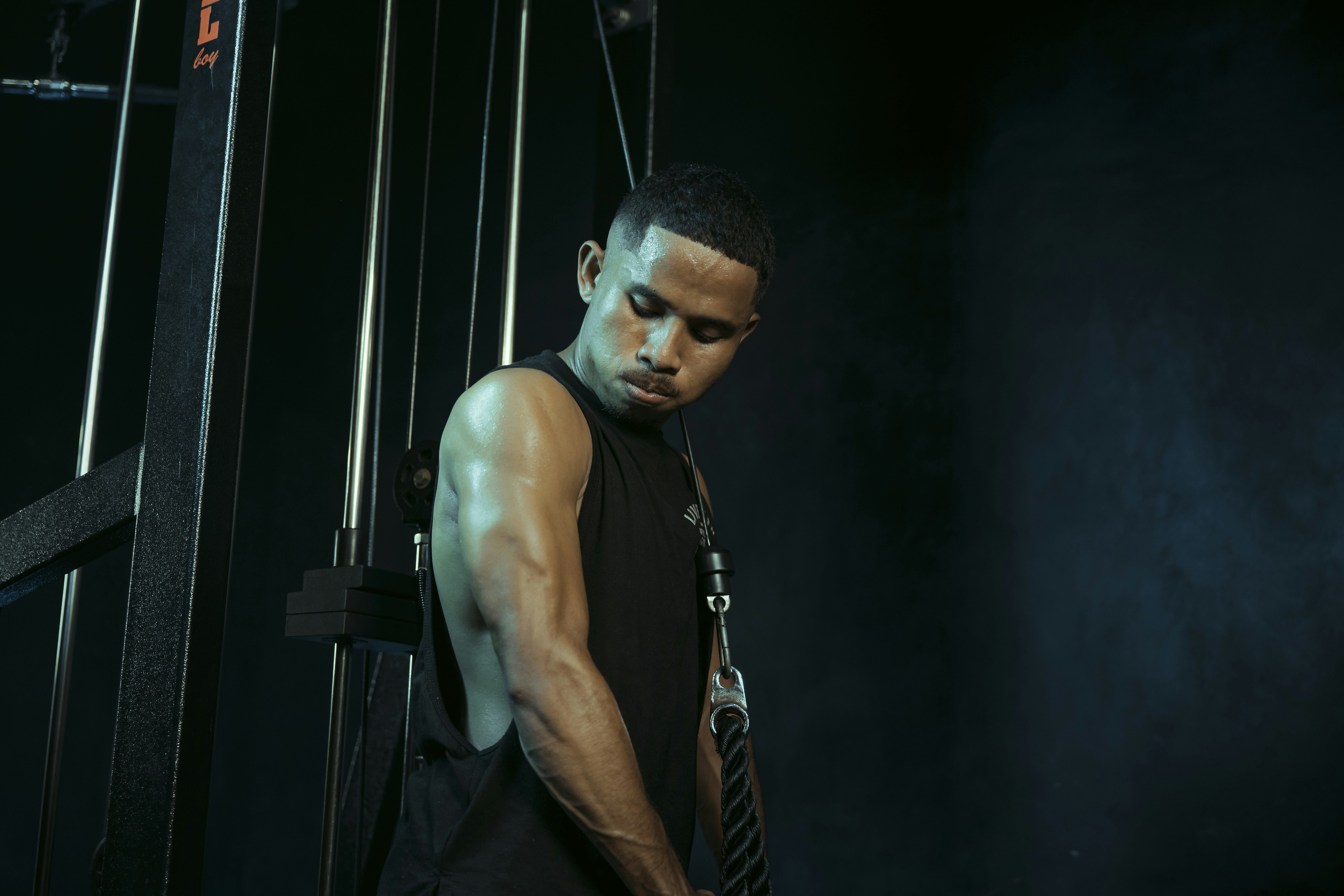 Man stands near gym equipment, looking down.