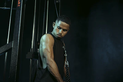 Man stands near gym equipment, looking down.