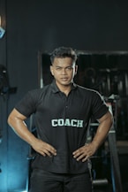 The gym coach is posing with hands on hips.