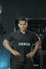 The gym coach is posing with hands on hips.