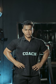 The gym coach is posing with hands on hips.