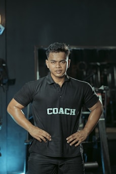 The gym coach is posing with hands on hips.