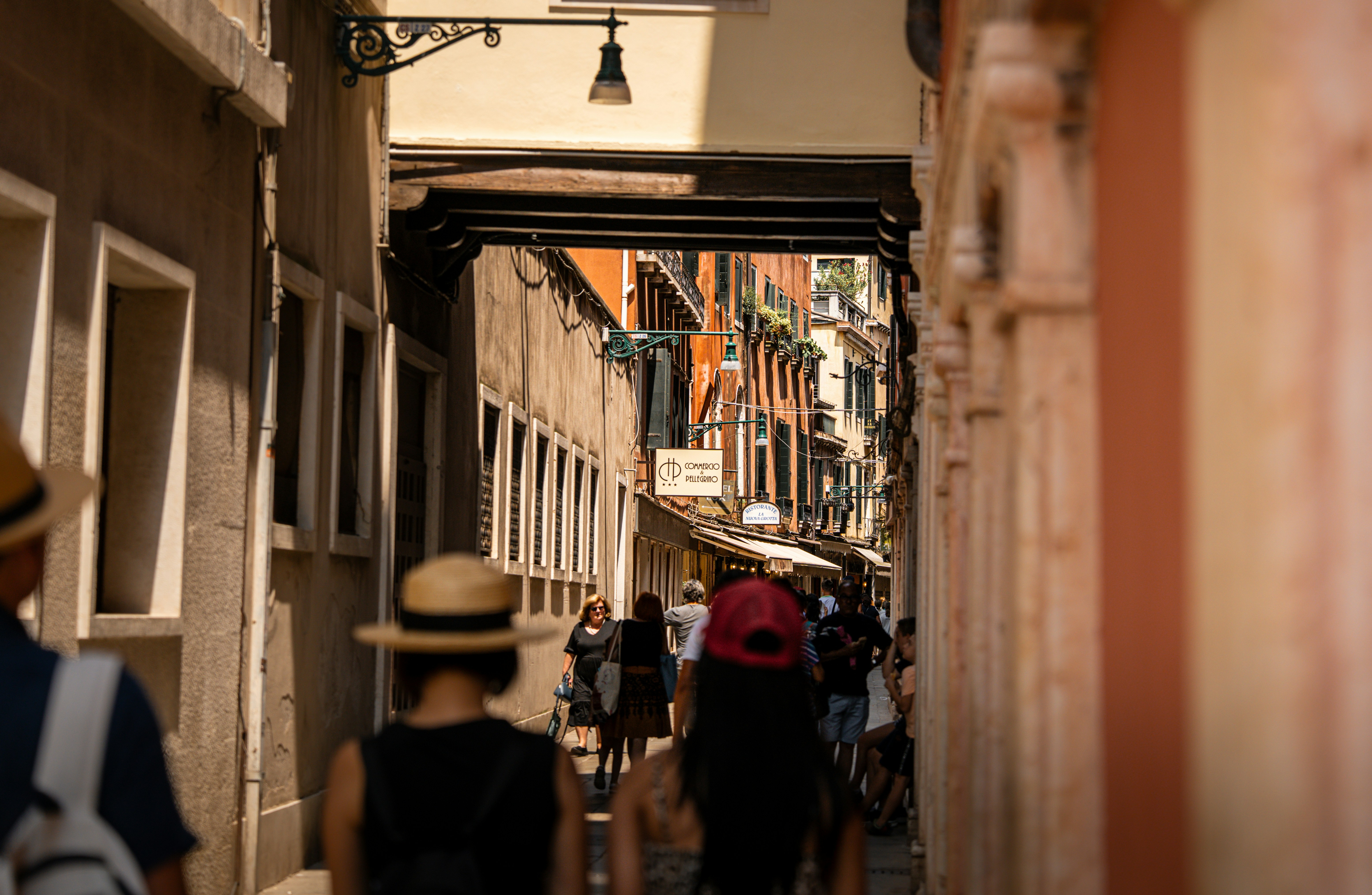 People walk down a narrow street in venice.