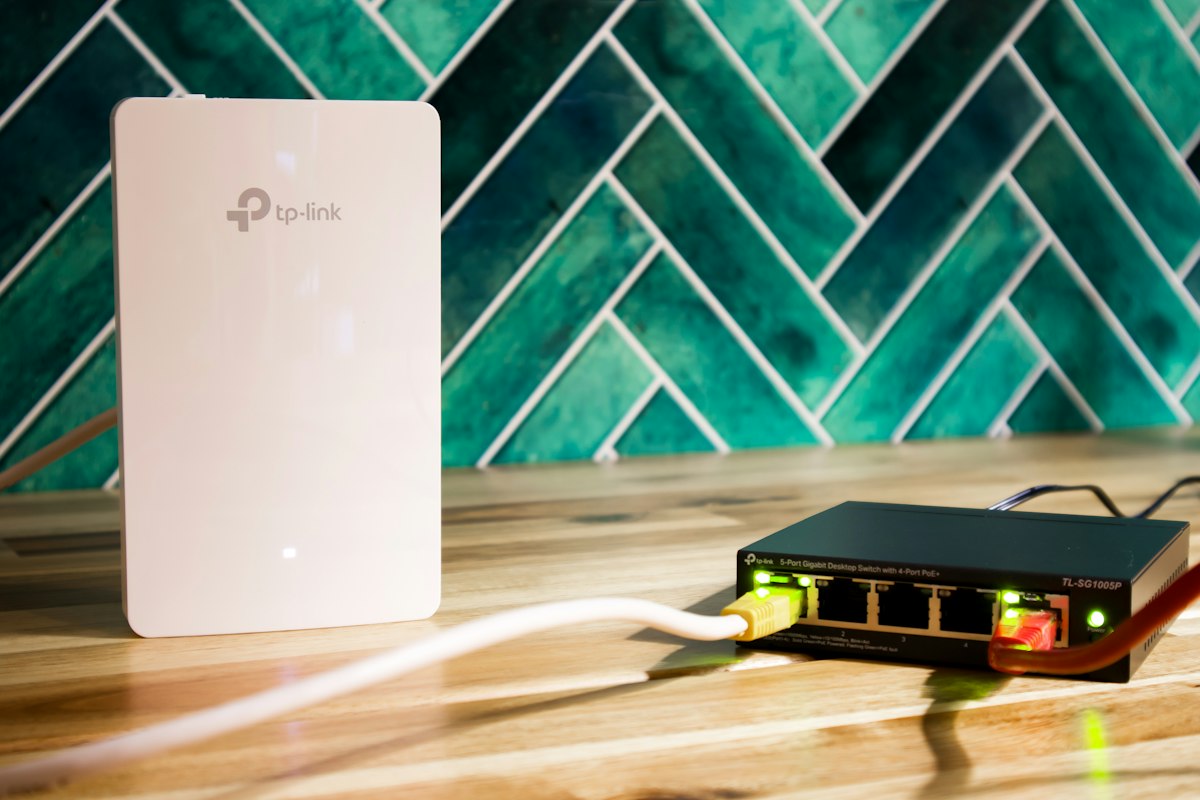 Router Wi-Fi e switch de rede lado a lado no armário de telecomunicações de uma casa