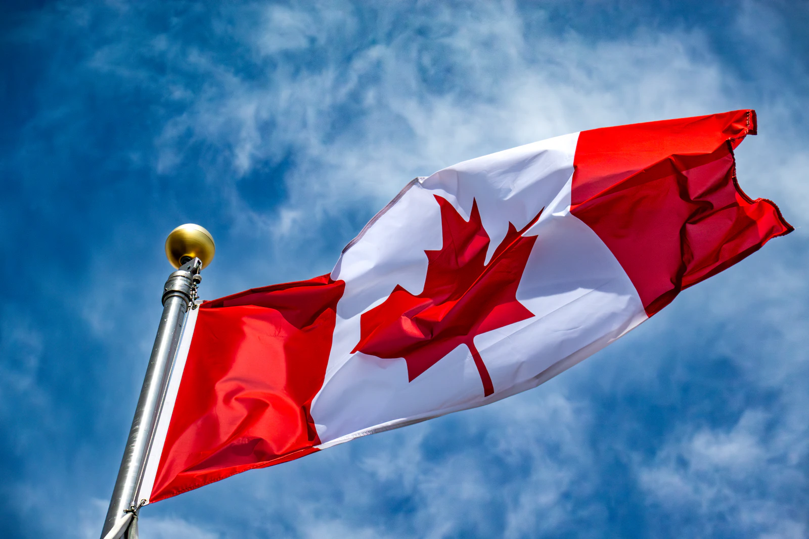 A Canadian flag waving against a clear blue sky