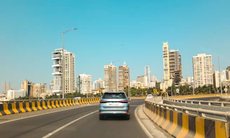A car drives toward city skyscrapers on a bridge.