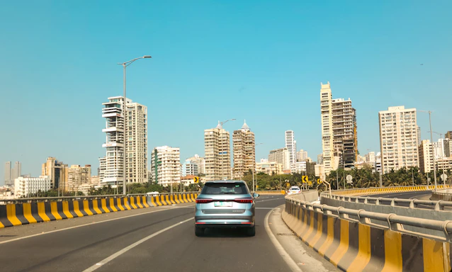 A car drives toward city skyscrapers on a bridge.