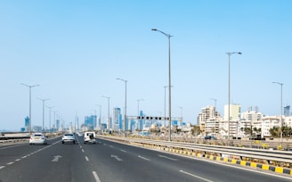 A highway with cars leads to a city skyline.